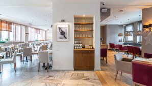 Un restaurante espacioso con techos altos, suelo de mármol y diversas opciones de asientos, incluyendo mesas y sillas.