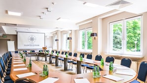 Un salón de conferencias con largas mesas, sillas y una pantalla de proyector mostrando el logotipo de Hotel Navigator.