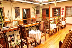 A traditional dining area with wooden furniture and a wooden railing. - Hotel Boutique Portal De Cantuña (Quito)