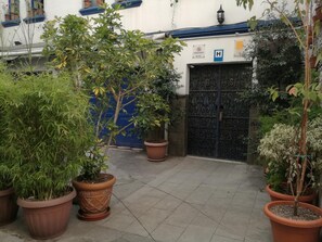 A courtyard with potted plants, a blue door, and a hospital sign. - Hotel Boutique Portal De Cantuña (Quito)