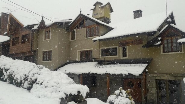 Een gebouw bedekt met sneeuw, met veel ramen en een houten gevel.