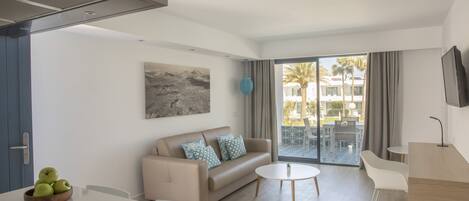 A modern living room with a sofa, a dining table, and a TV.