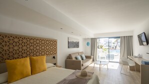 Ein modernes Hotelzimmer mit einem großen Bett, einer Couch, einem Schreibtisch und einem Balkon mit Blick auf die Stadt.