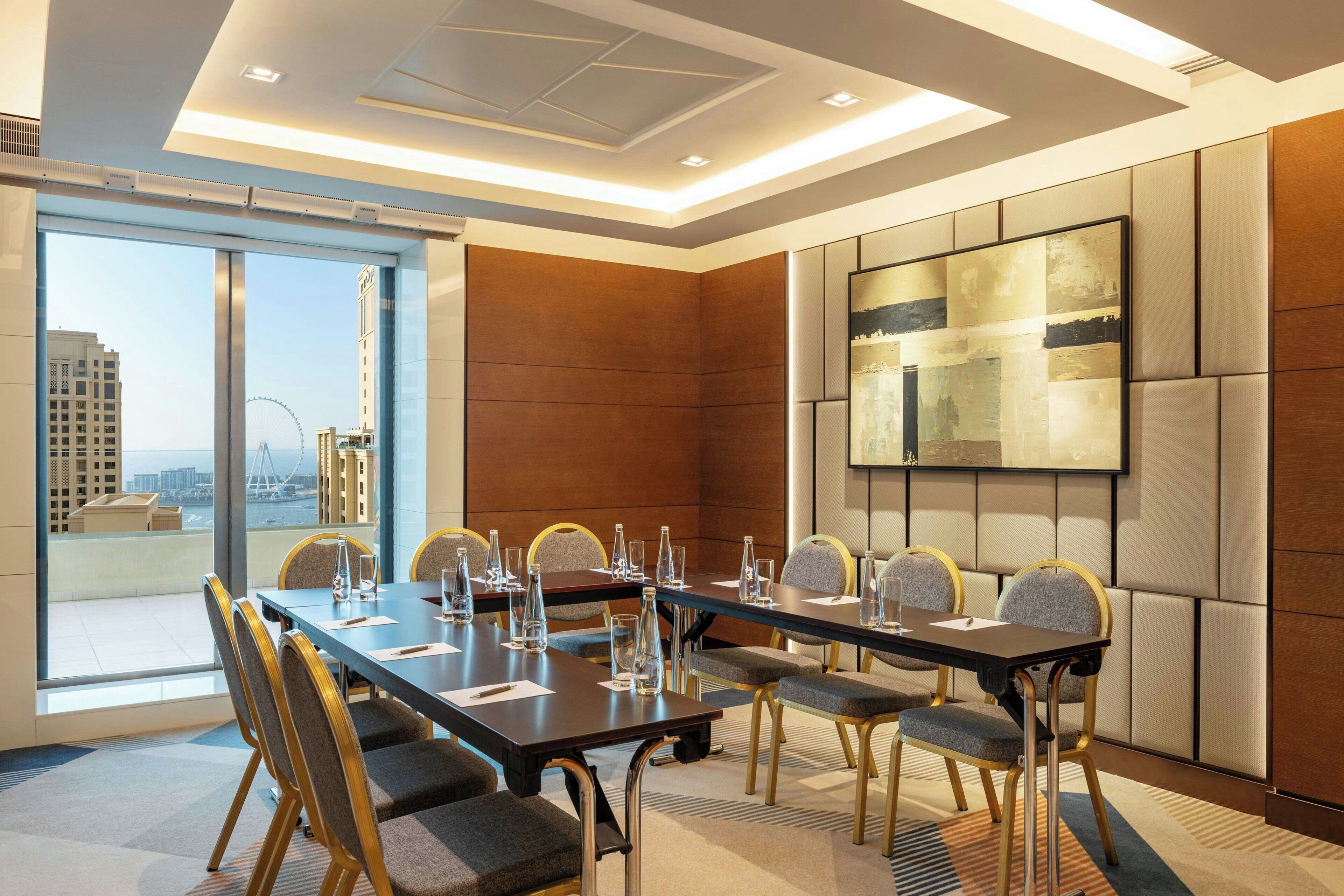 A conference room with a long table, chairs, and a city view through large windows.