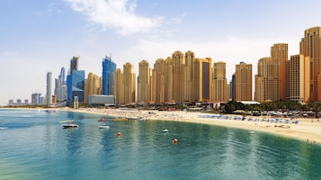 Una playa cerca, arena blanca, sombrillas, toallas de playa