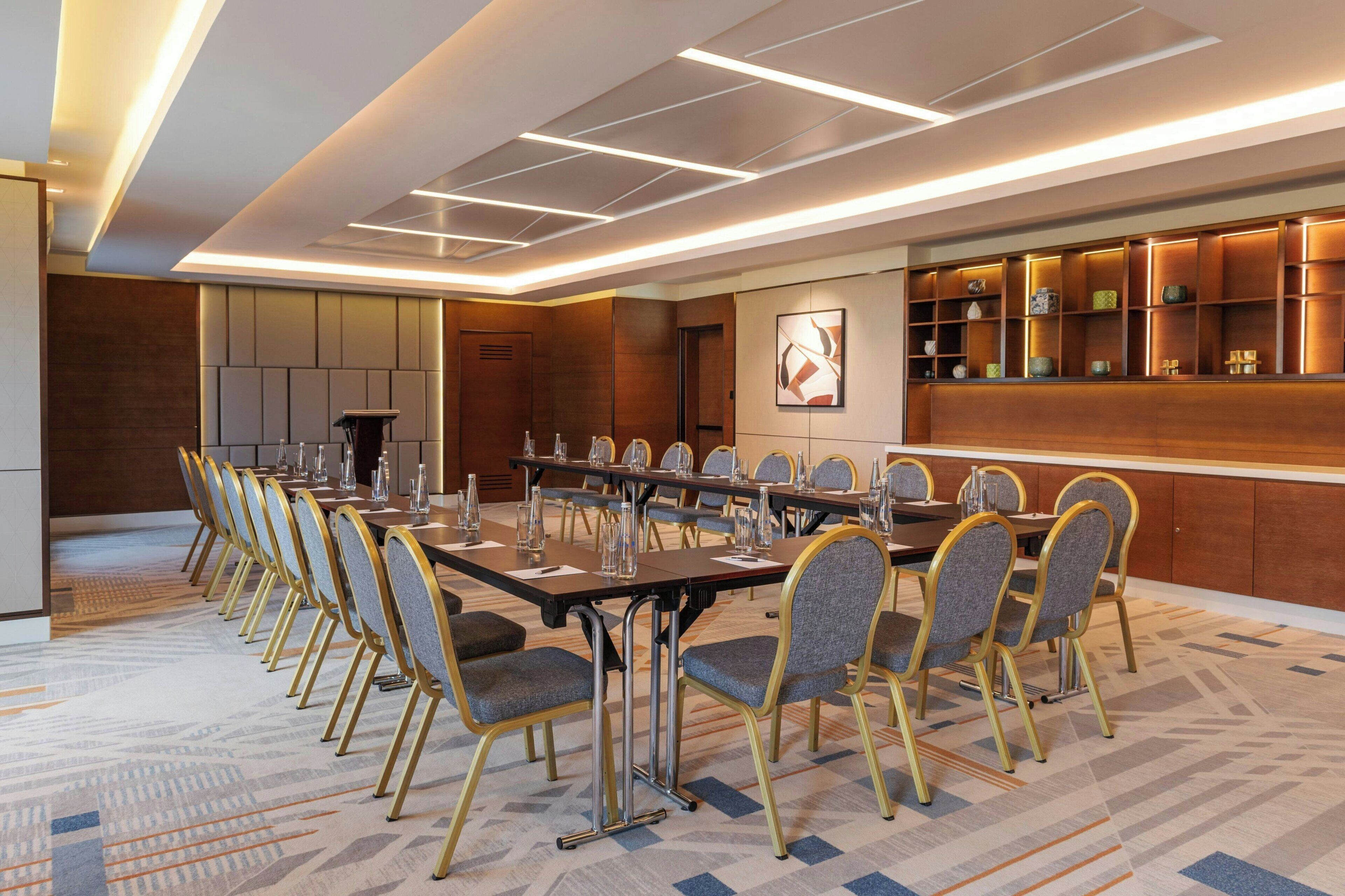 A conference room with a long table, multiple chairs, and a decorative wall with shelves.