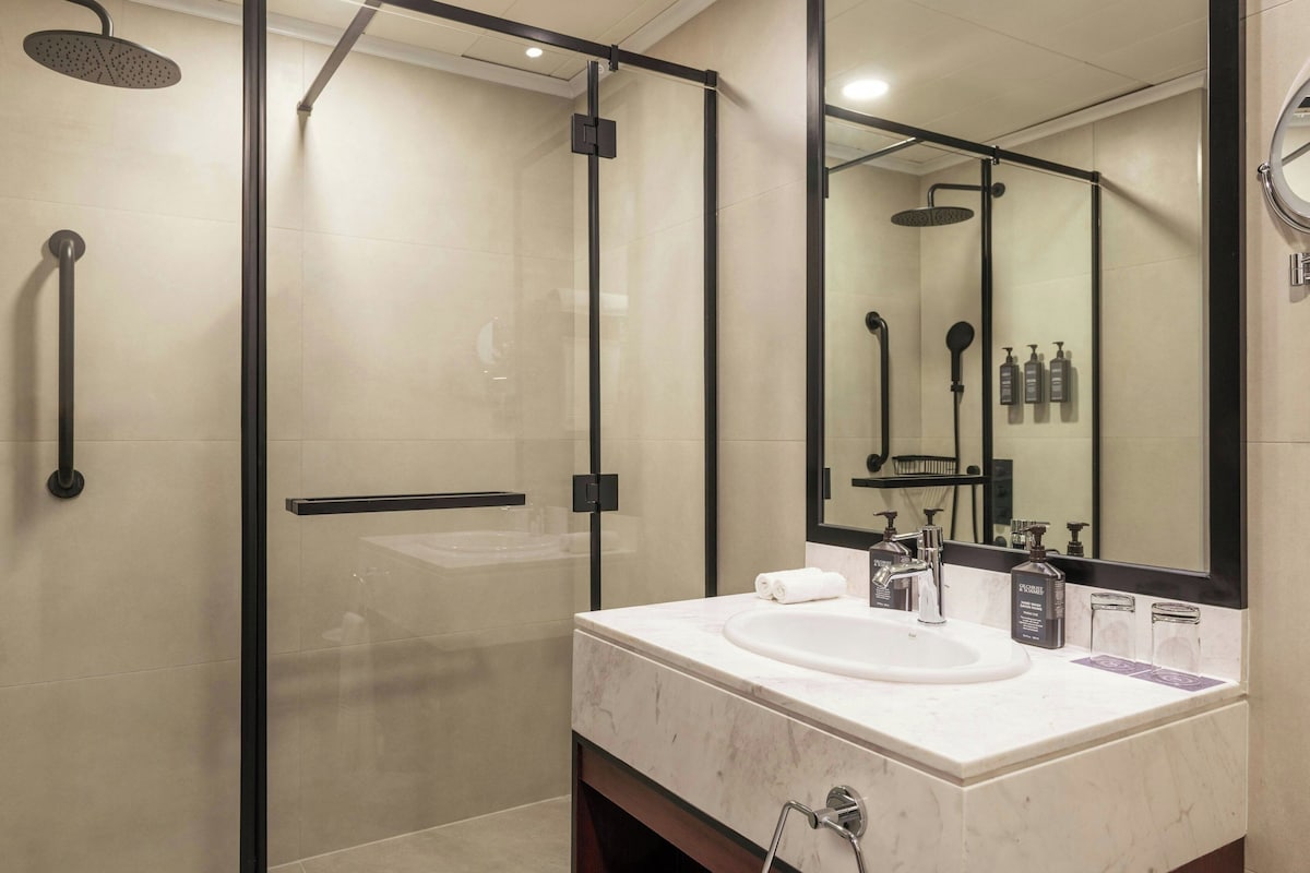 Une salle de bain moderne avec une douche à parois de verre, un lavabo blanc et un grand miroir.