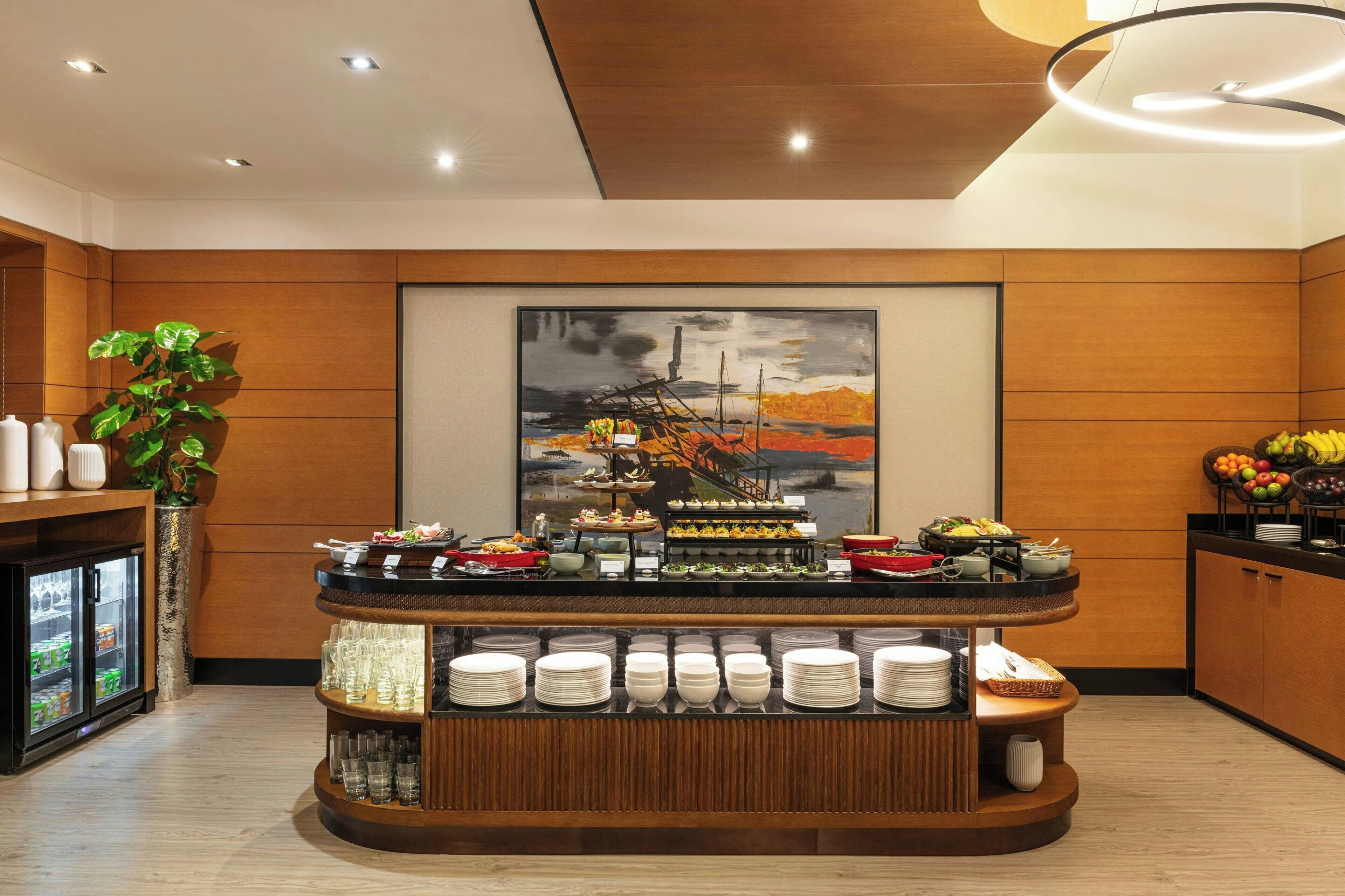 A buffet setup with various food items and a painting on the wall.
