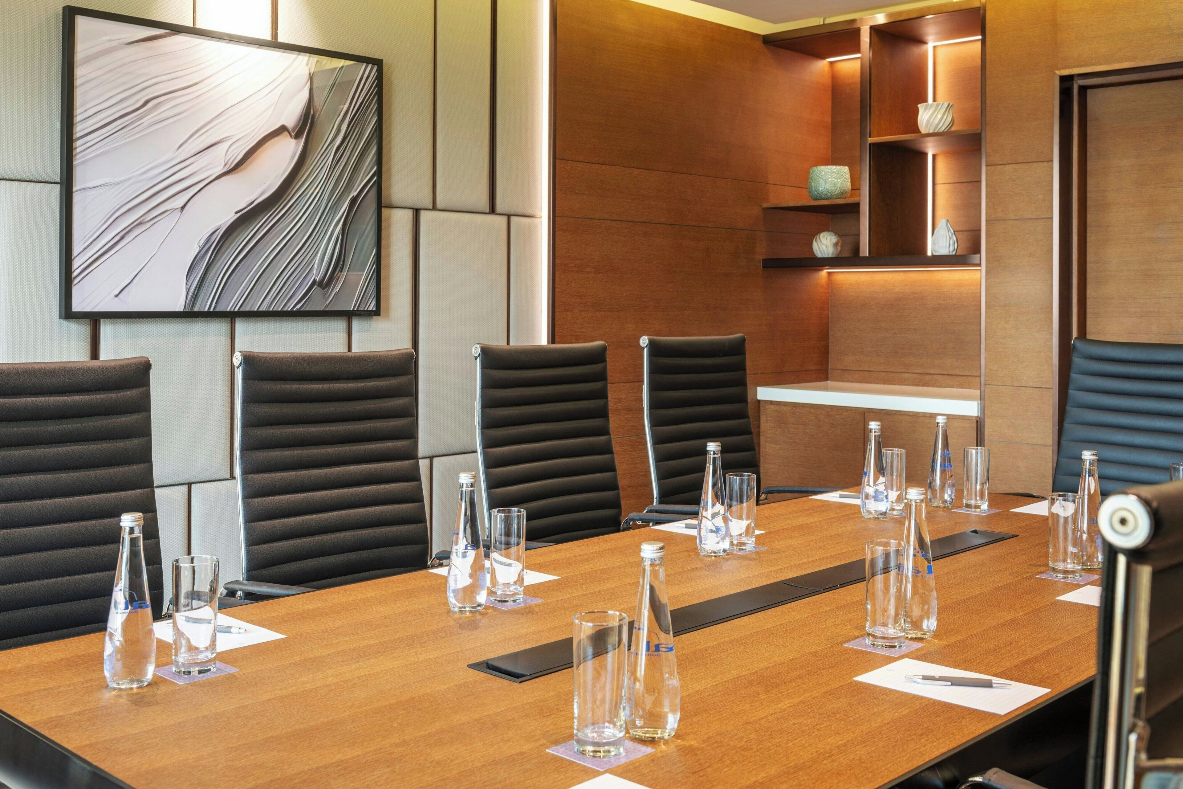 A conference room with a long table, six chairs, and water bottles.