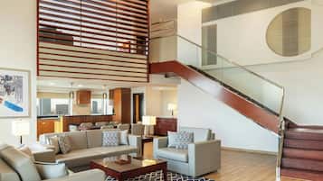A modern living room with a staircase, a sofa set, a coffee table, and a patterned rug.