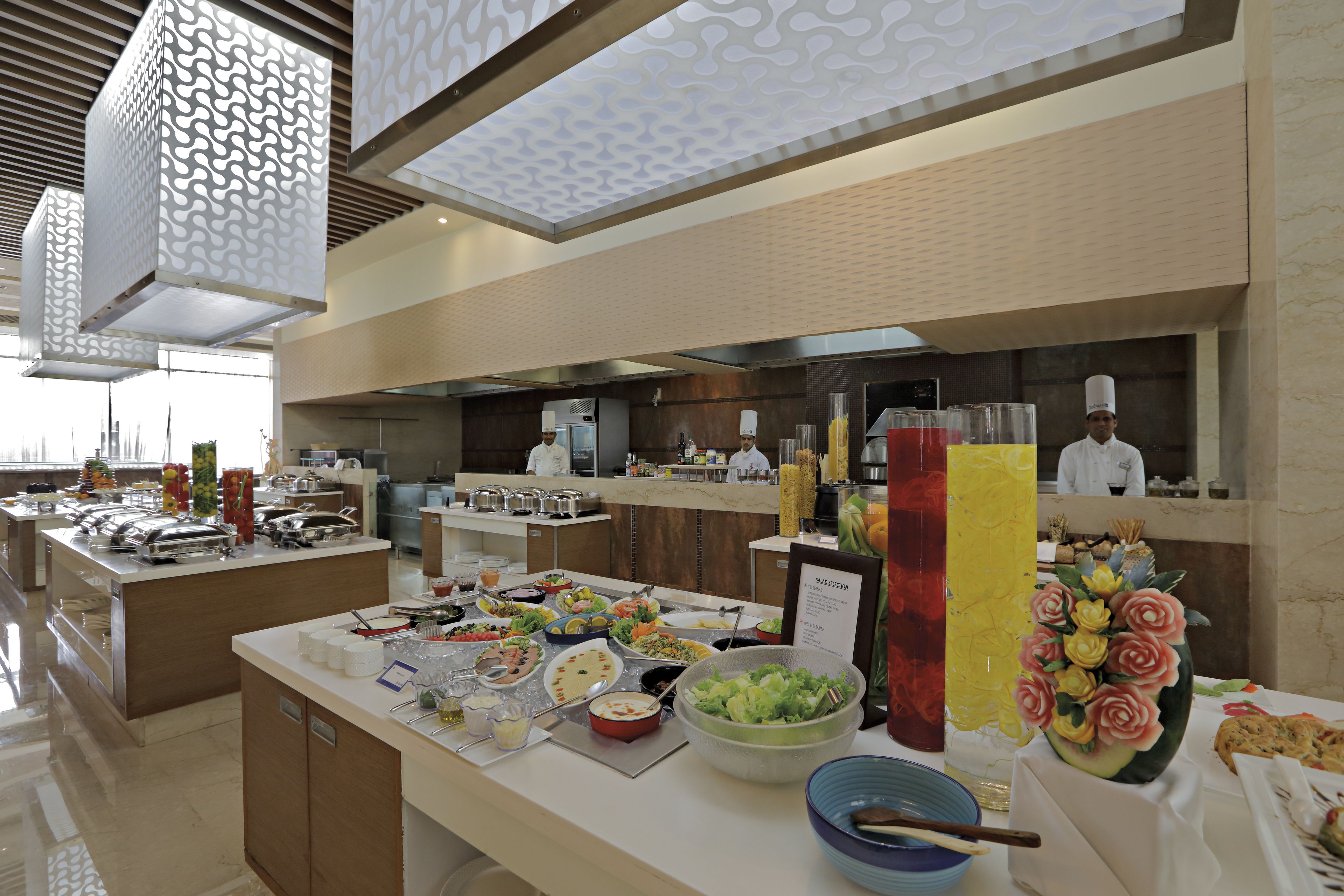 Una mesa de buffet con diversos alimentos y un chef al fondo.