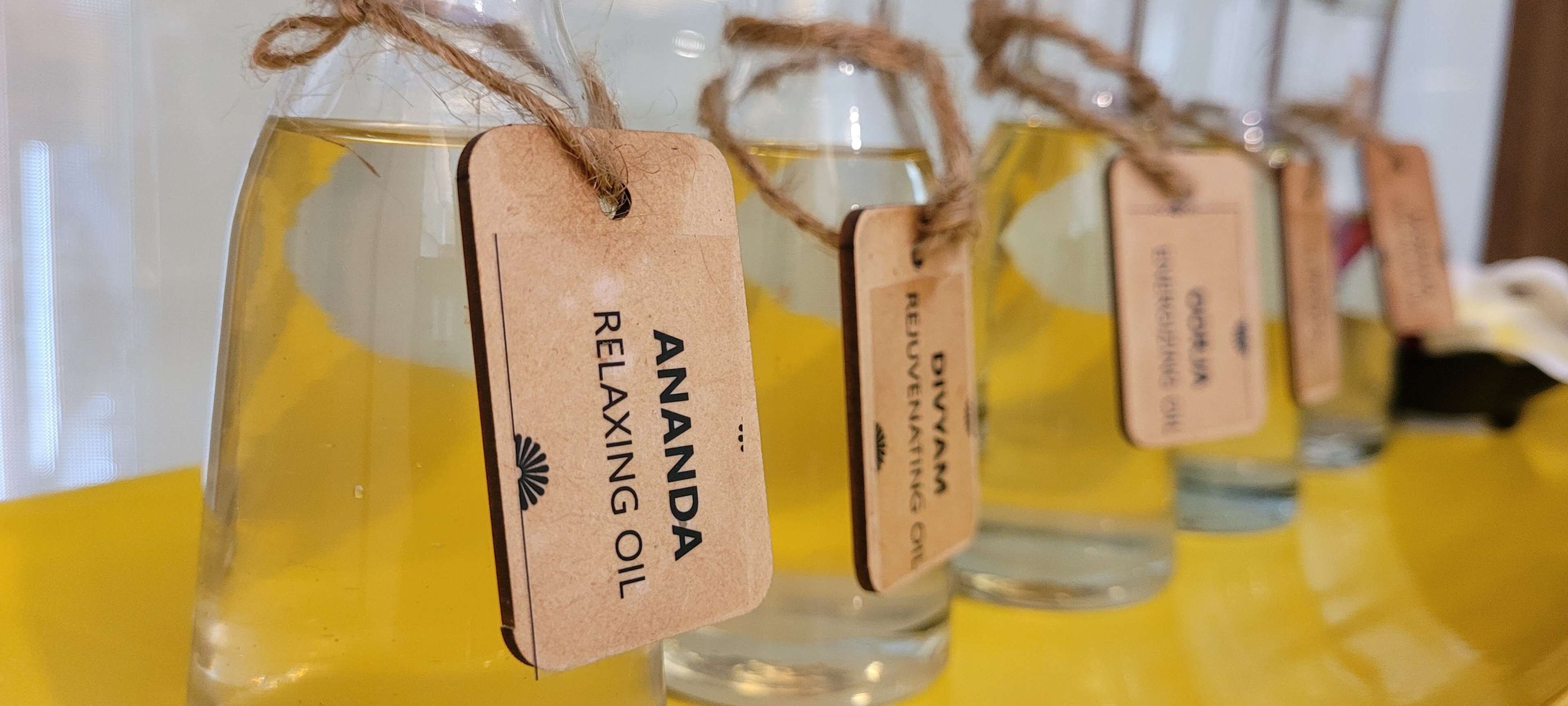 Een rij glazen flesjes met labels met de tekst 'Ananda Relaxing Oil'.
