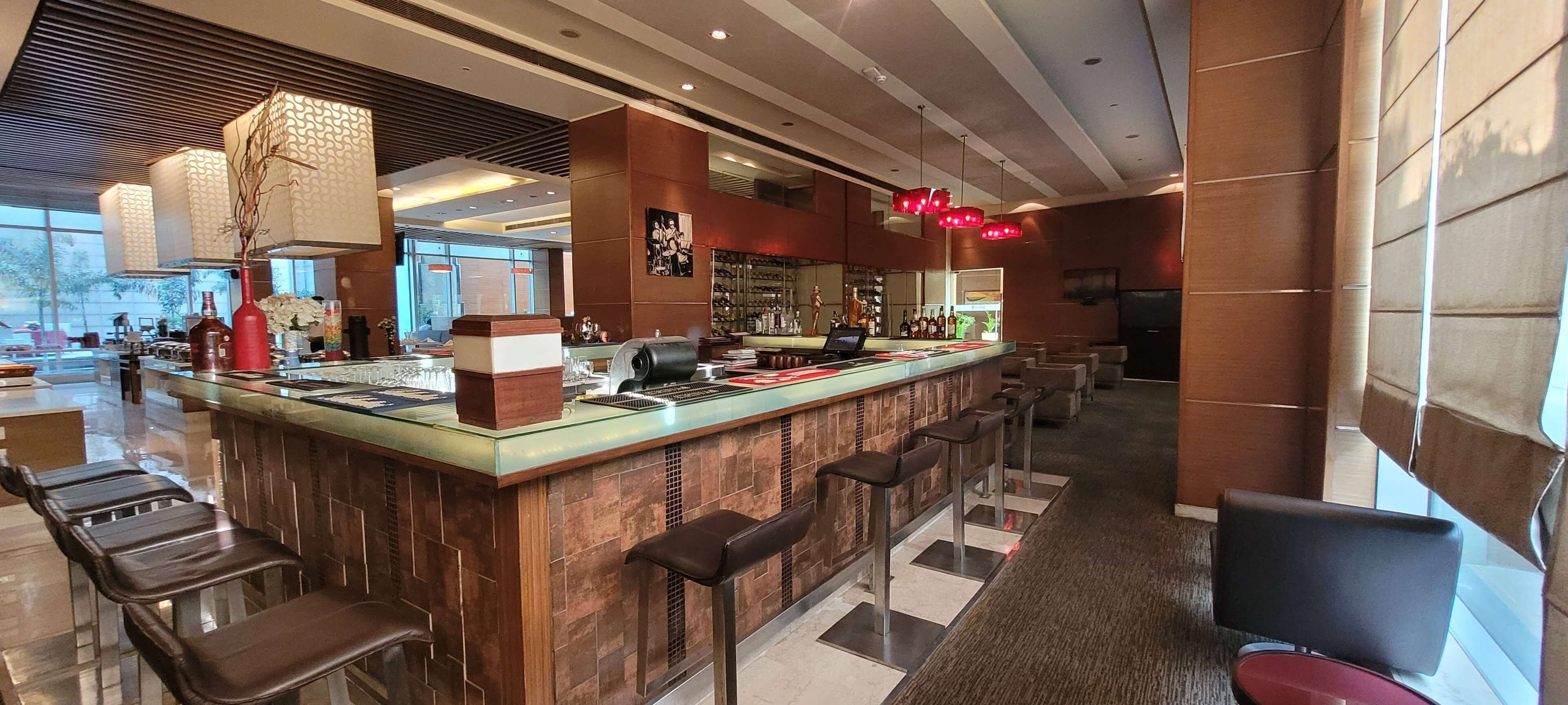 A modern bar area with a long counter, multiple bar stools, and a seating area with chairs.