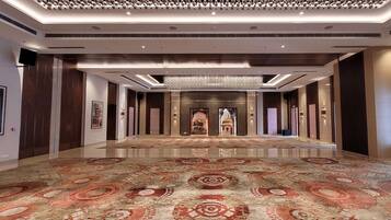 Un vaste hall d’entrée agrémenté d’un tapis à motifs, d’un lustre et d’œuvres d’art encadrées qui ornent les murs.