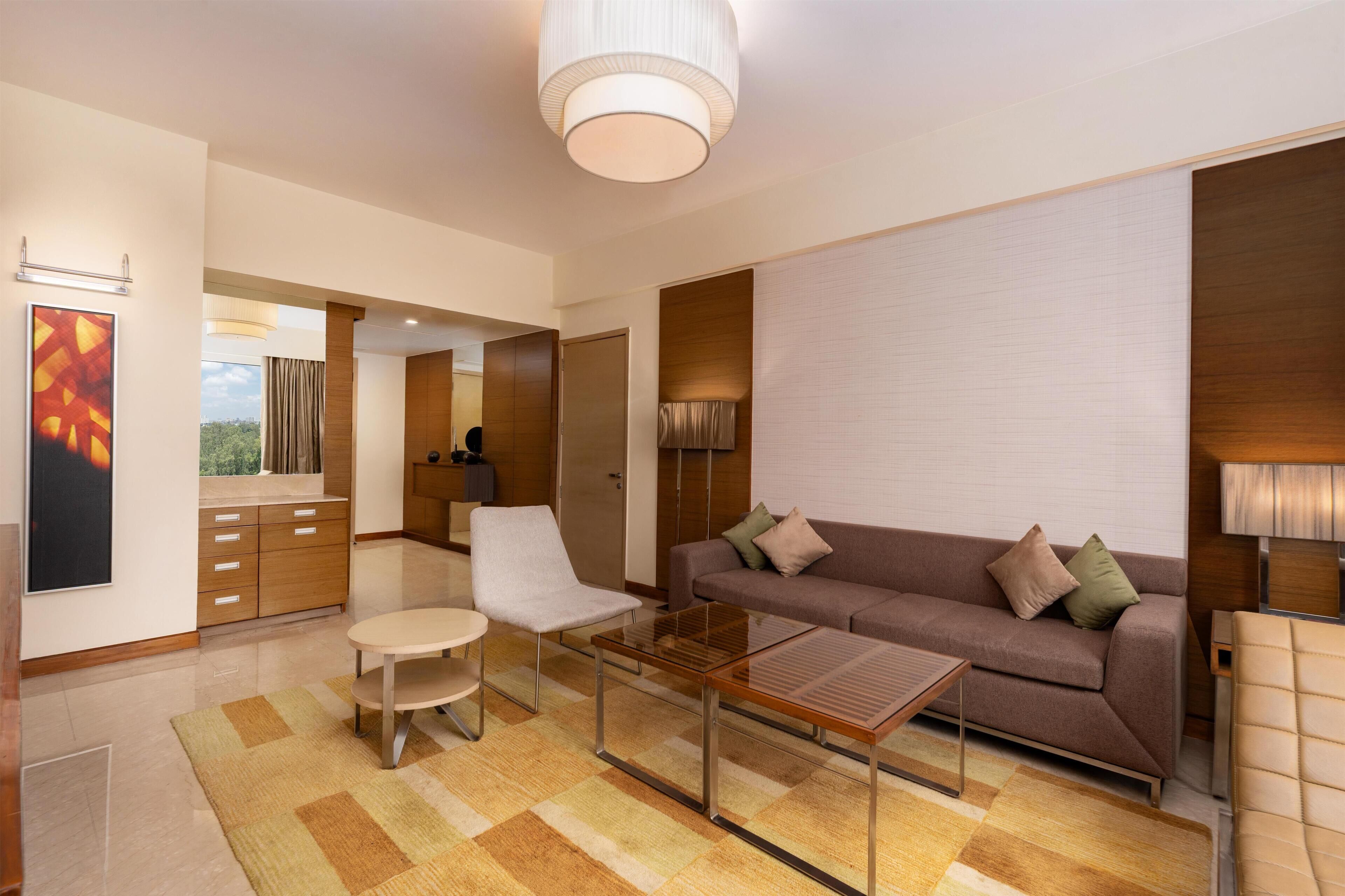 A modern living room with a sofa, armchair, coffee table, and a view of the outdoors.