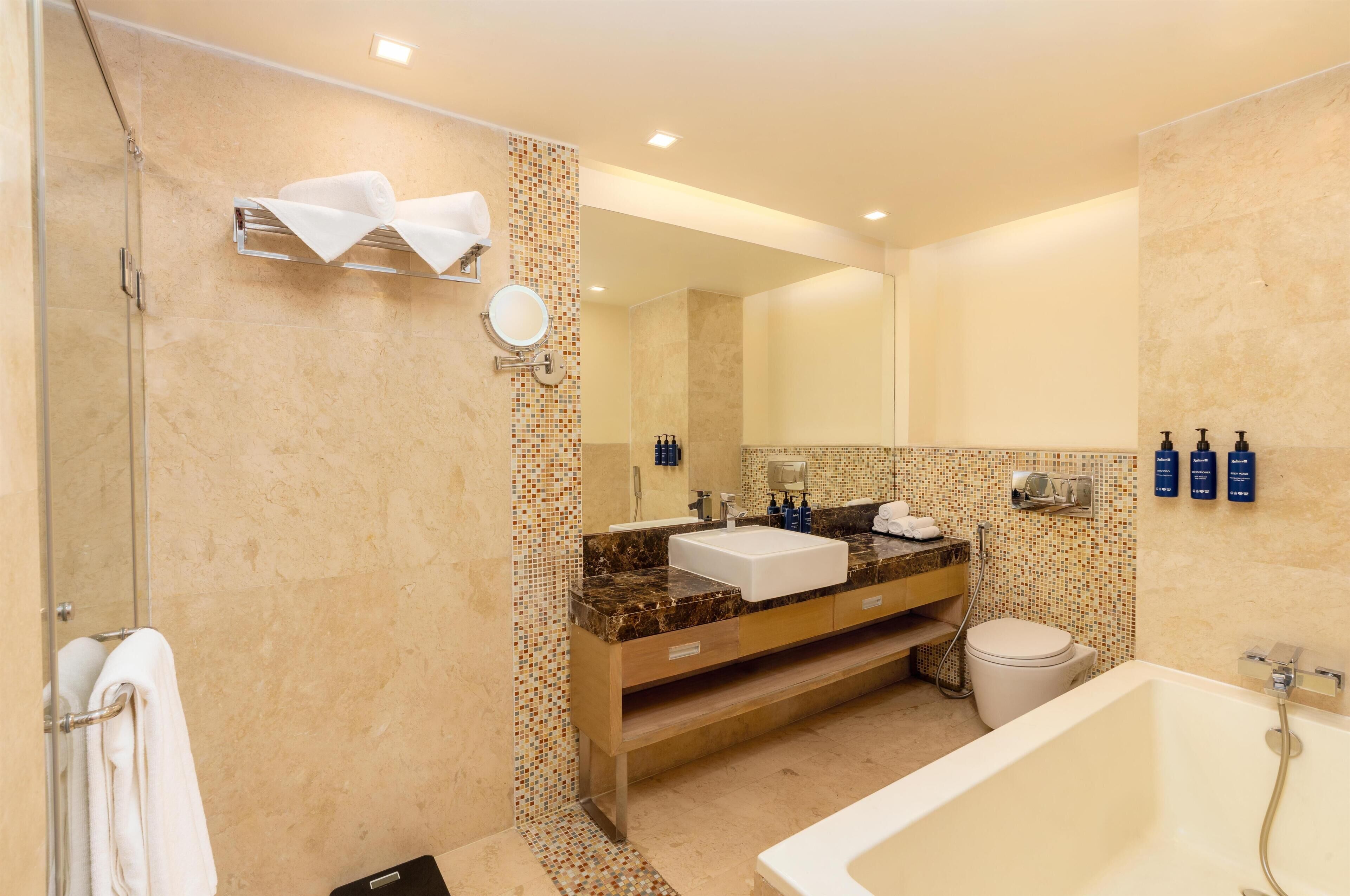 A modern bathroom with a shower, sink, toilet, and bathtub.