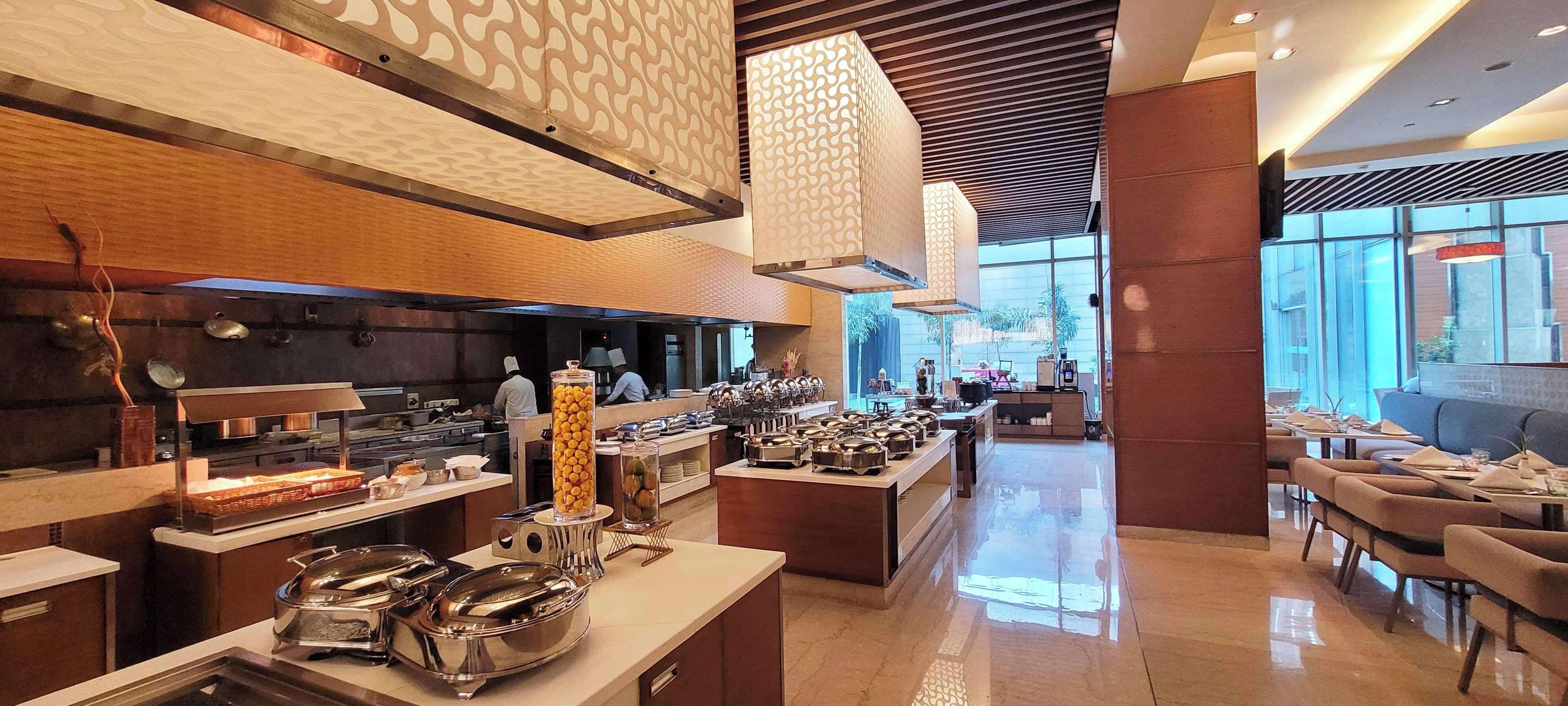 Una hall d'albergo moderna con un'area buffet, posti a sedere e ampie finestre che offrono una vista panoramica.