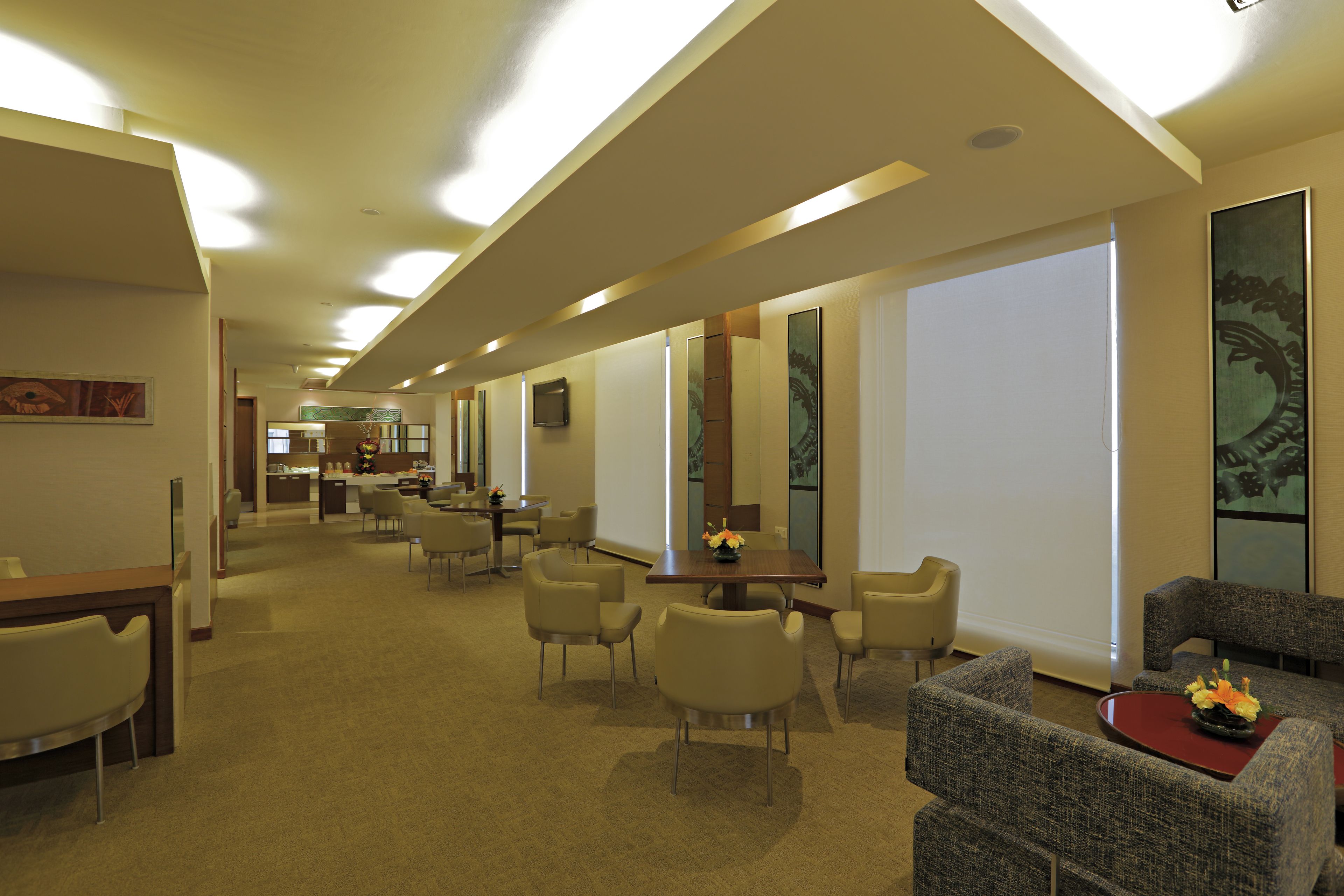 Una hall d'albergo con una lunga reception, diverse aree salotto e ampie finestre che offrono luce naturale.