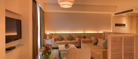 A modern hotel room with a sofa set, a coffee table, a TV, and a decorative vase.