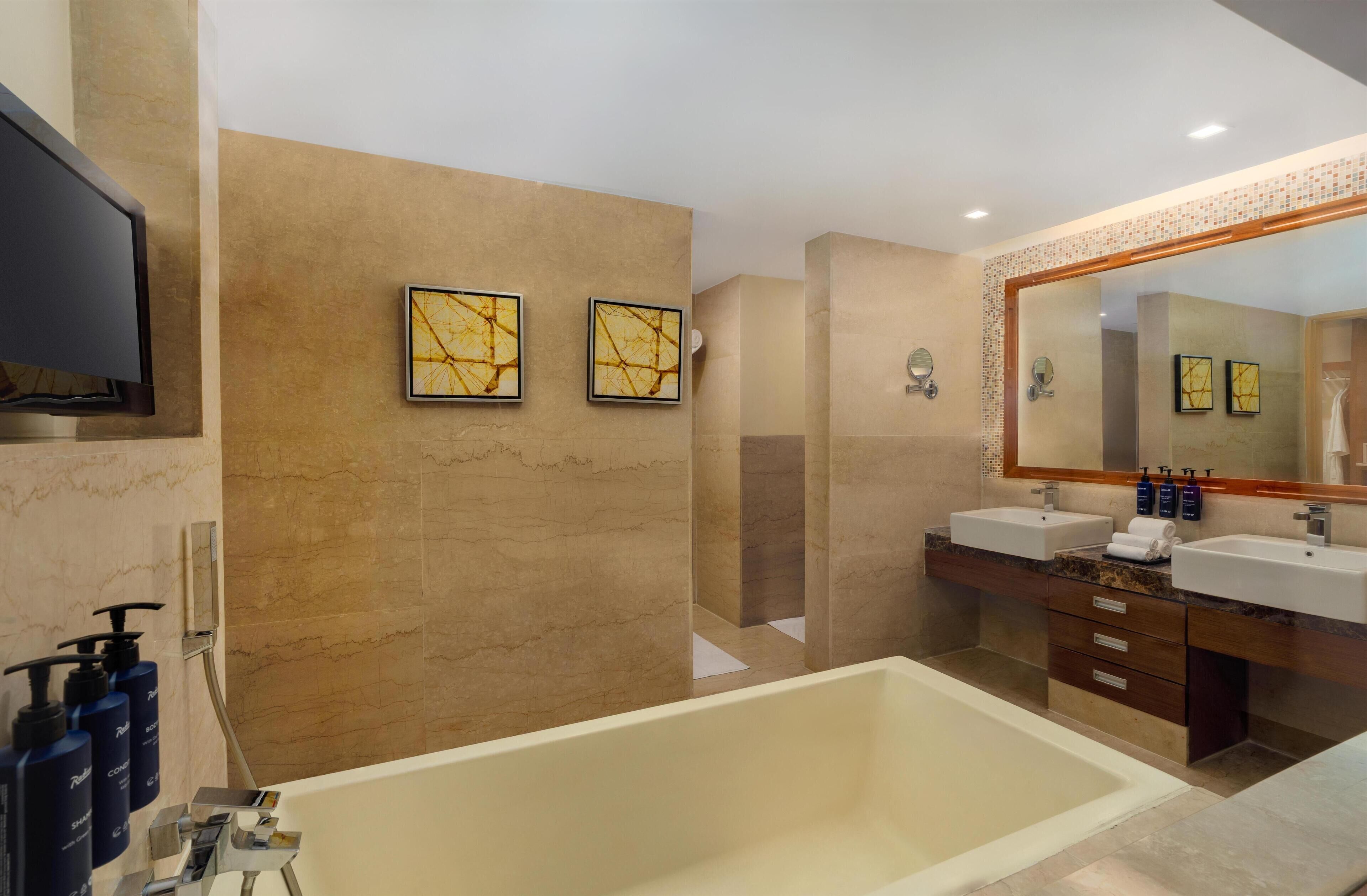 A modern bathroom with a large bathtub, two sinks, and a large mirror.