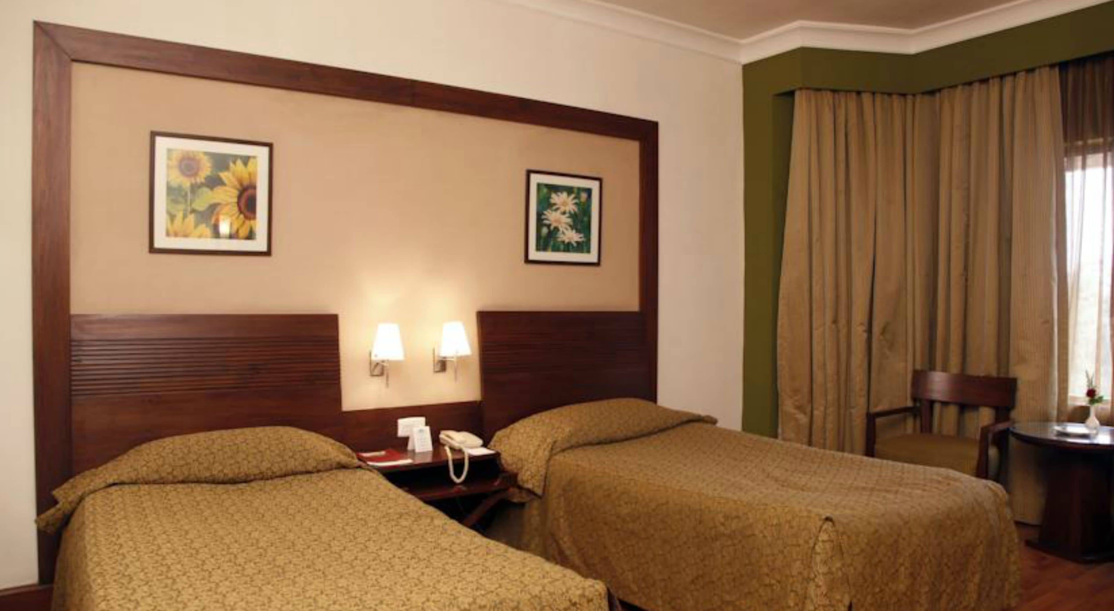Camera d'albergo con due letti, un comodino con il telefono e due lampade a parete.