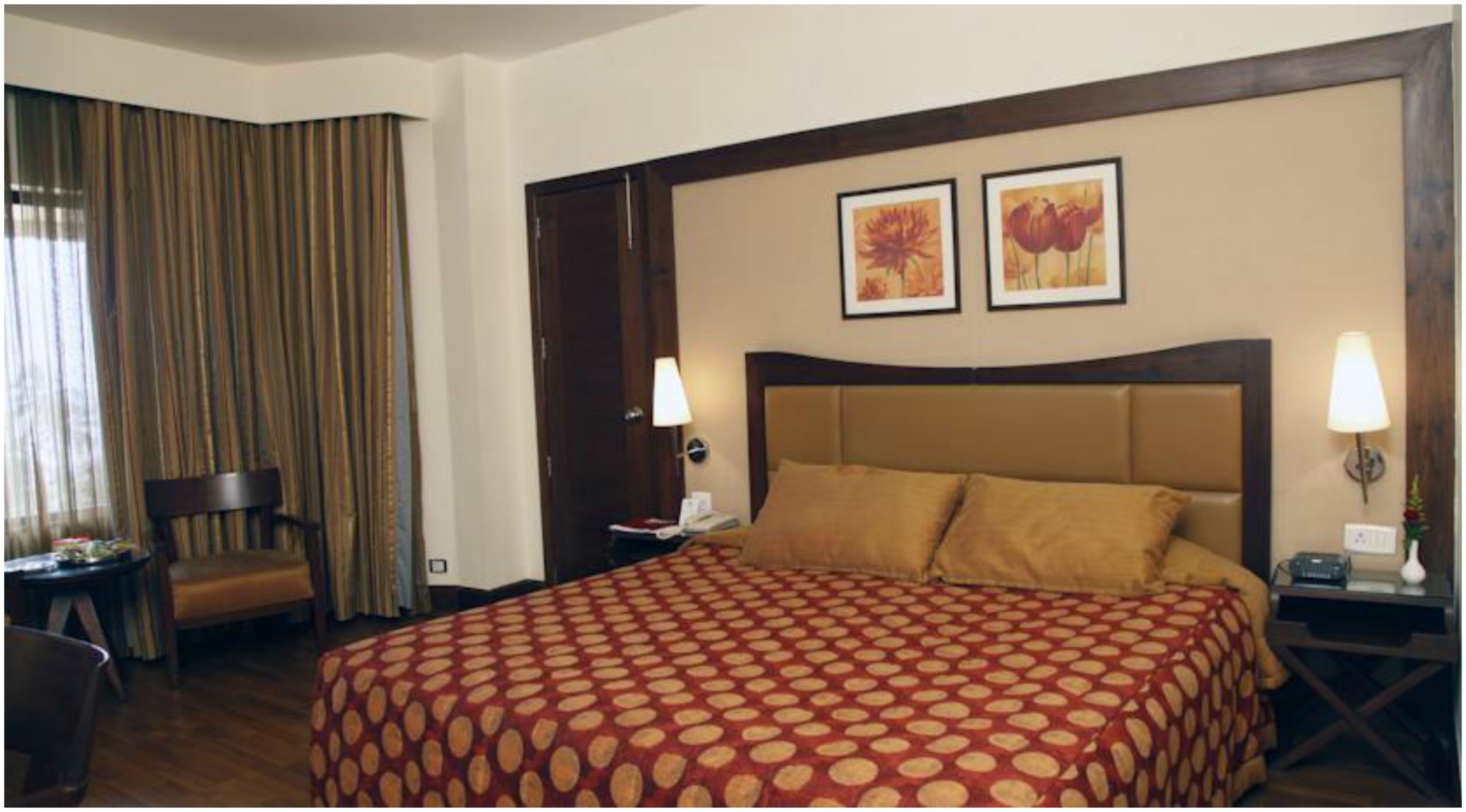 A hotel room with a large bed, two wall-mounted lamps, a chair, and a window with curtains.