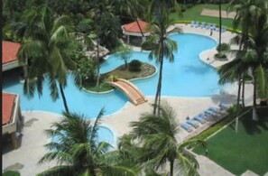 A resort with a large swimming pool, palm trees, and a small bridge. - The Retreat Hotel & Convention Centre (Mumbai)