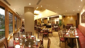 Un restaurante con varias zonas de comedor, incluyendo un área con asientos tipo cabina y varias mesas con sillas.