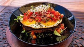 A bowl of food with a fried egg on top, surrounded by various vegetables and sprouts.