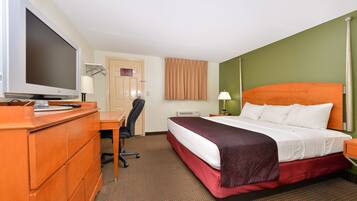 Habitación de hotel con cama, escritorio, silla, televisor y lámpara.