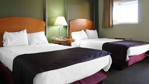 Ein Hotelzimmer mit zwei Betten, einem Nachttisch, einer Lampe und einem Fenster mit Vorhängen.