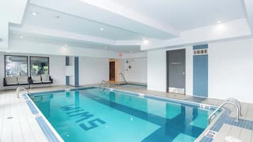 Una gran piscina interior con agua cristalina azul, paredes de azulejos y un diseño moderno.
