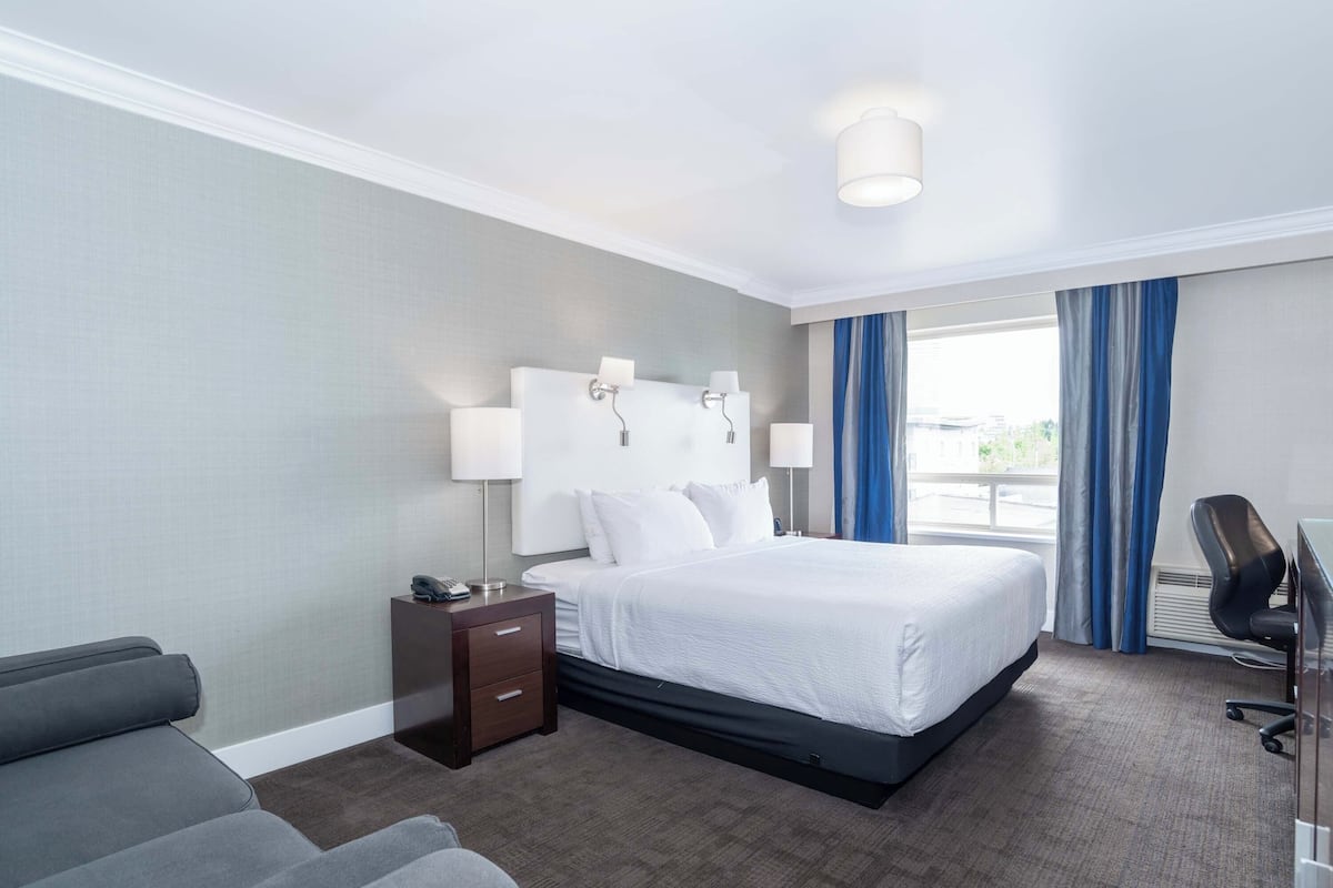 A hotel room with a large bed, bedside lamps, a desk, and a chair.