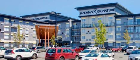Un hotel Signature Sandman con un estacionamiento lleno de coches.