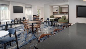 A modern hotel lobby with round tables, chairs, a bar area, and a seating area with a sofa and chairs. - Fairfield Inn & Suites Baltimore BWI Airport (Linthicum Heights)
