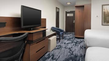Habitación de hotel con televisión de pantalla plana, escritorio con silla, cama y armario.