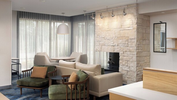 A modern living room with a stone accent wall, a fireplace, and a large window with sheer curtains. - Fairfield Inn & Suites Baltimore BWI Airport (Linthicum Heights)