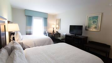 Une chambre d’hôtel avec deux lits, un bureau, une télévision et un banc.