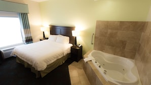 A hotel room with a large bed, bedside lamps, a bathtub, and a window with curtains.