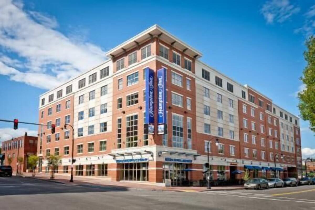 A multi-story hotel with a central entrance, large windows, and a flat roof.