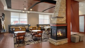 A modern lounge area with a fireplace, seating, and a large window.