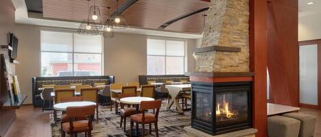 A modern lounge area with a fireplace, seating, and a large window.
