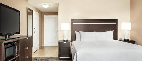 A hotel room with a bed, bedside tables with lamps, a TV on a cabinet, and a microwave.