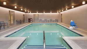 A large indoor swimming pool with a wooden ceiling and tiled walls.