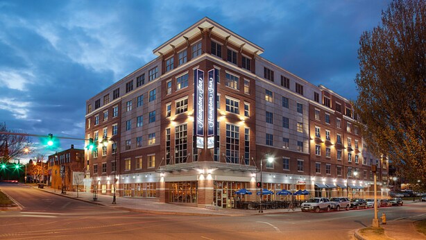 A multi-story hotel with a prominent entrance, large windows, and a well-lit facade.