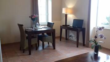 Un coin repas avec une table dressée pour deux personnes, une lampe, un ordinateur portable et une orchidée en pot.