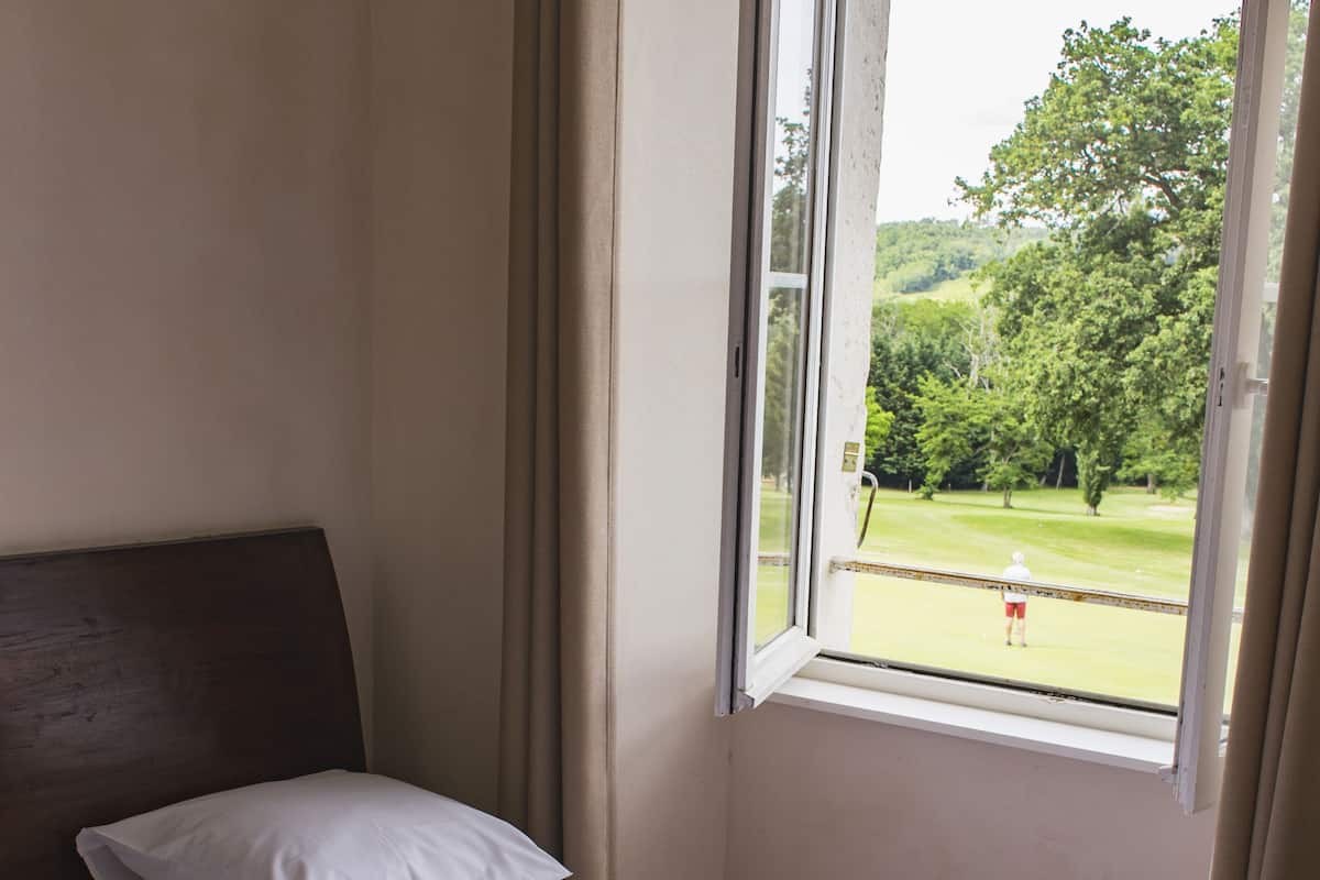 Une chambre d’hôtel avec un lit, une fenêtre et une vue sur un paysage verdoyant.