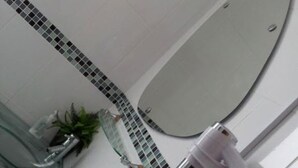 A bathroom with a large mirror, a glass shower enclosure, and a towel rack. - Priory Guest House (Cleethorpes)