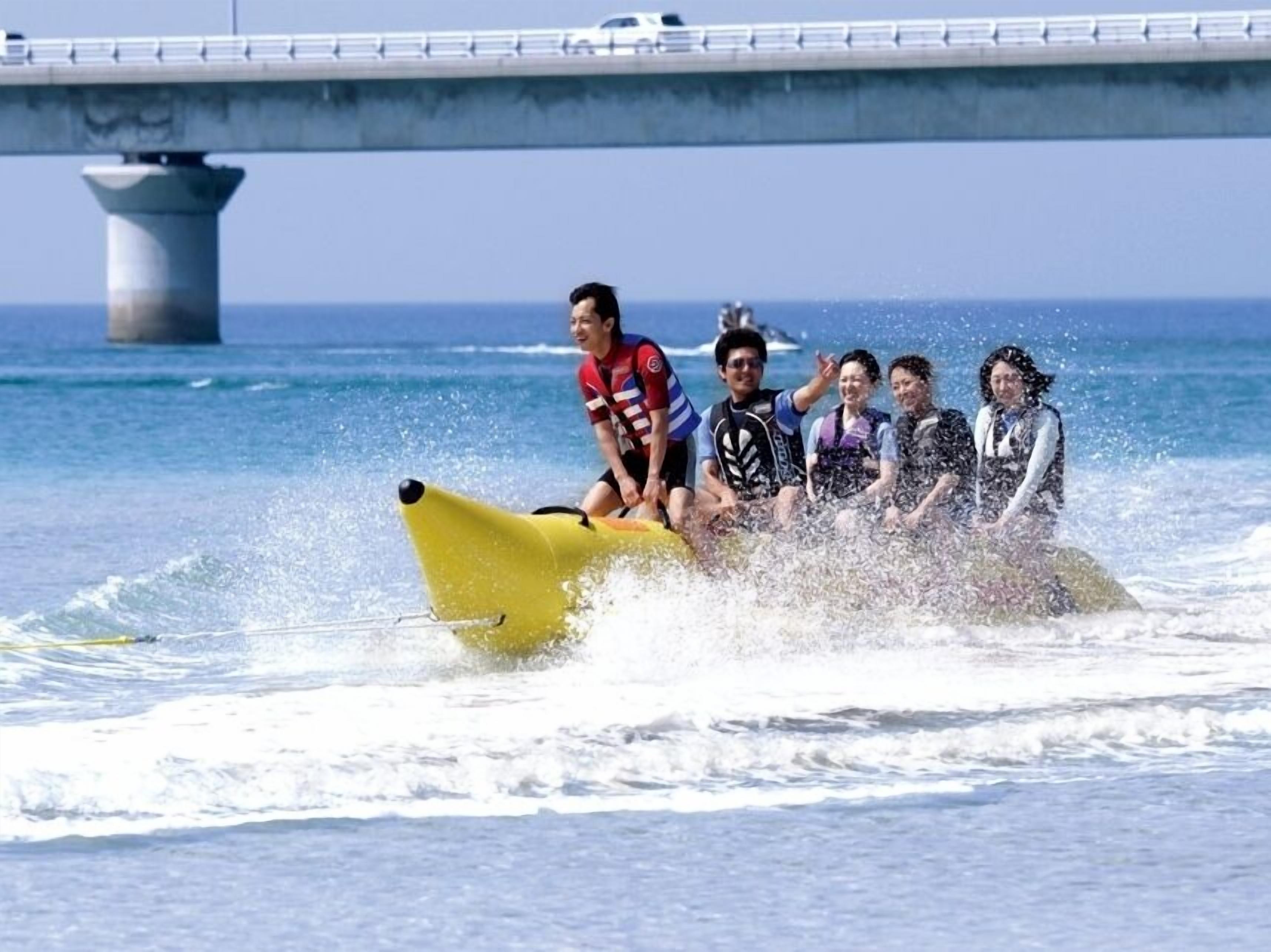 A group of people on a yellow jet ski in the ocean, with a bridge in the background.