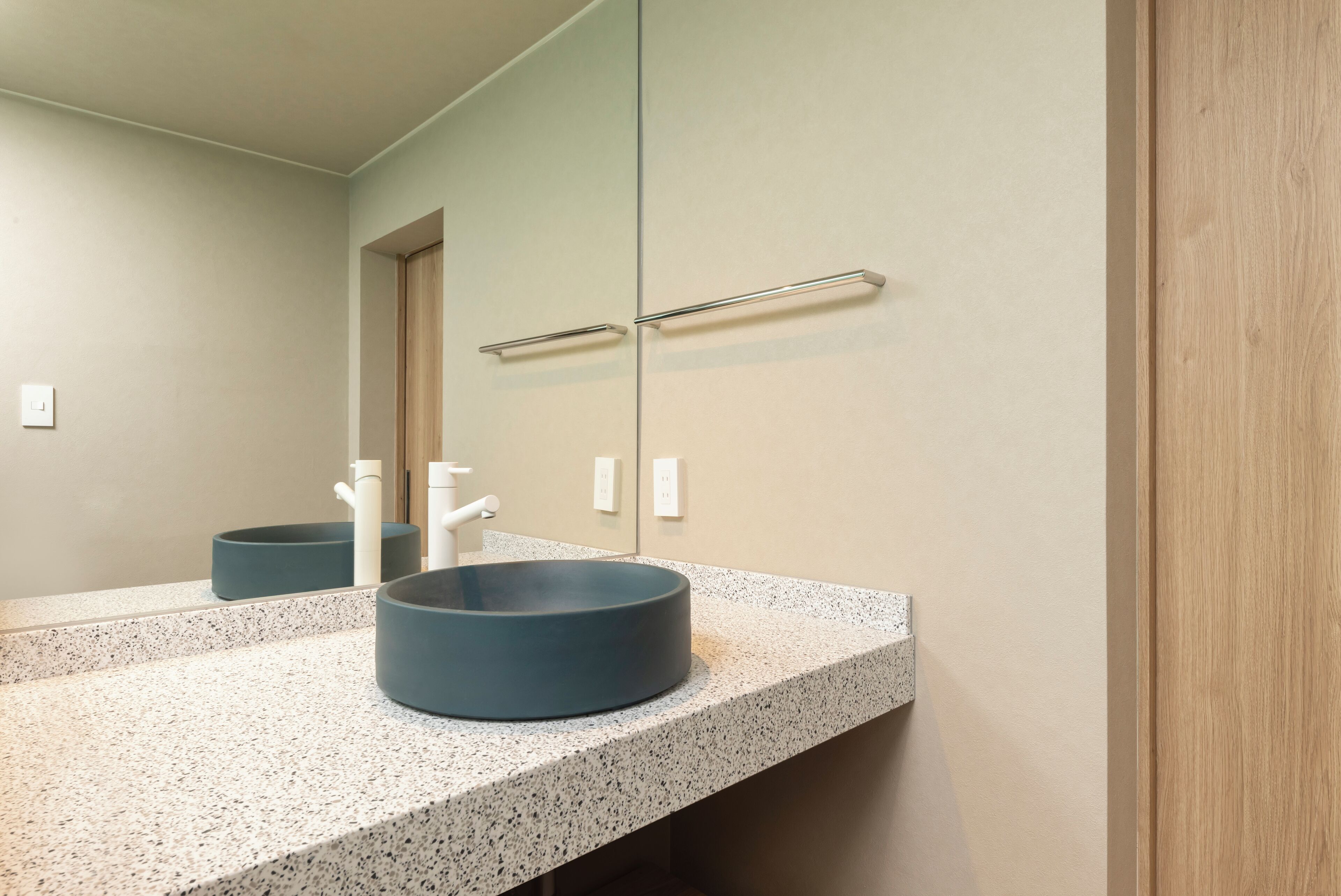 A bathroom with a granite countertop, a round sink, and a mirror.